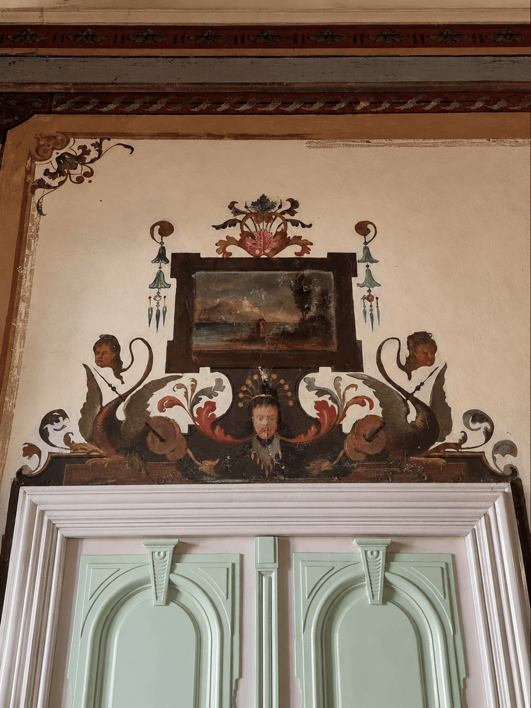 Ornate fresco above a mint-green doorway